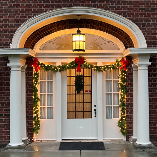 Entrance way to the manor with holiday greens, red bows, and white lights